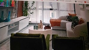 A modern living room with a round coffee table, a sofa, and two green armchairs. - Luxury suites polanco  (Ciudad de México)