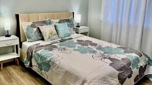A bedroom with a bed, nightstands, a lamp, and a window with curtains.