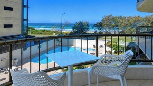 A balcony with a view of a swimming pool and the ocean. - Beachside 1BR Ocean View Apartment with Parking (Broadbeach)