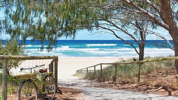 A beach path leading to the ocean with a bicycle parked by the gate. - Beachside 1BR Ocean View Apartment with Parking (Broadbeach)