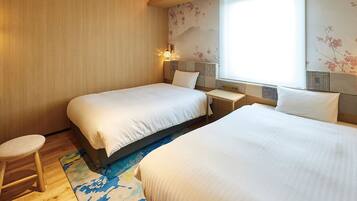 A hotel room with two beds, a desk, and a chair. There are wall-mounted lamps and a large window with a view of cherry blossoms.