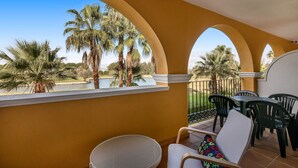 A balcony with a view of palm trees and a body of water.