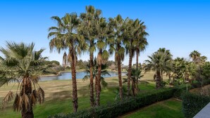 A golf course with palm trees and a body of water.