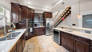 Una cocina moderna con gabinetes de madera oscura, electrodomésticos de acero inoxidable y un horno empotrado.