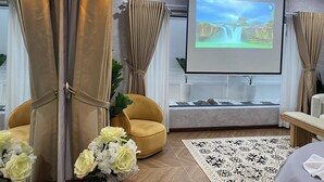 Une pièce moderne dotée d’un grand écran diffusant une image de cascade, d’un fauteuil jaune et d’une plante en pot.
