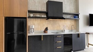 Una cocina moderna con un refrigerador negro, armarios oscuros, una encimera blanca y un horno empotrado.