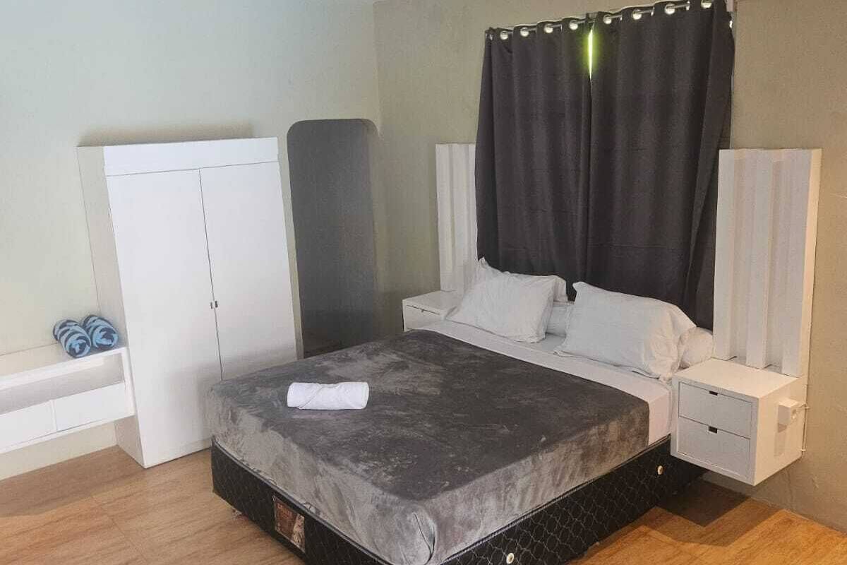 A bedroom with a bed, a wardrobe, a nightstand, and an air conditioning unit.