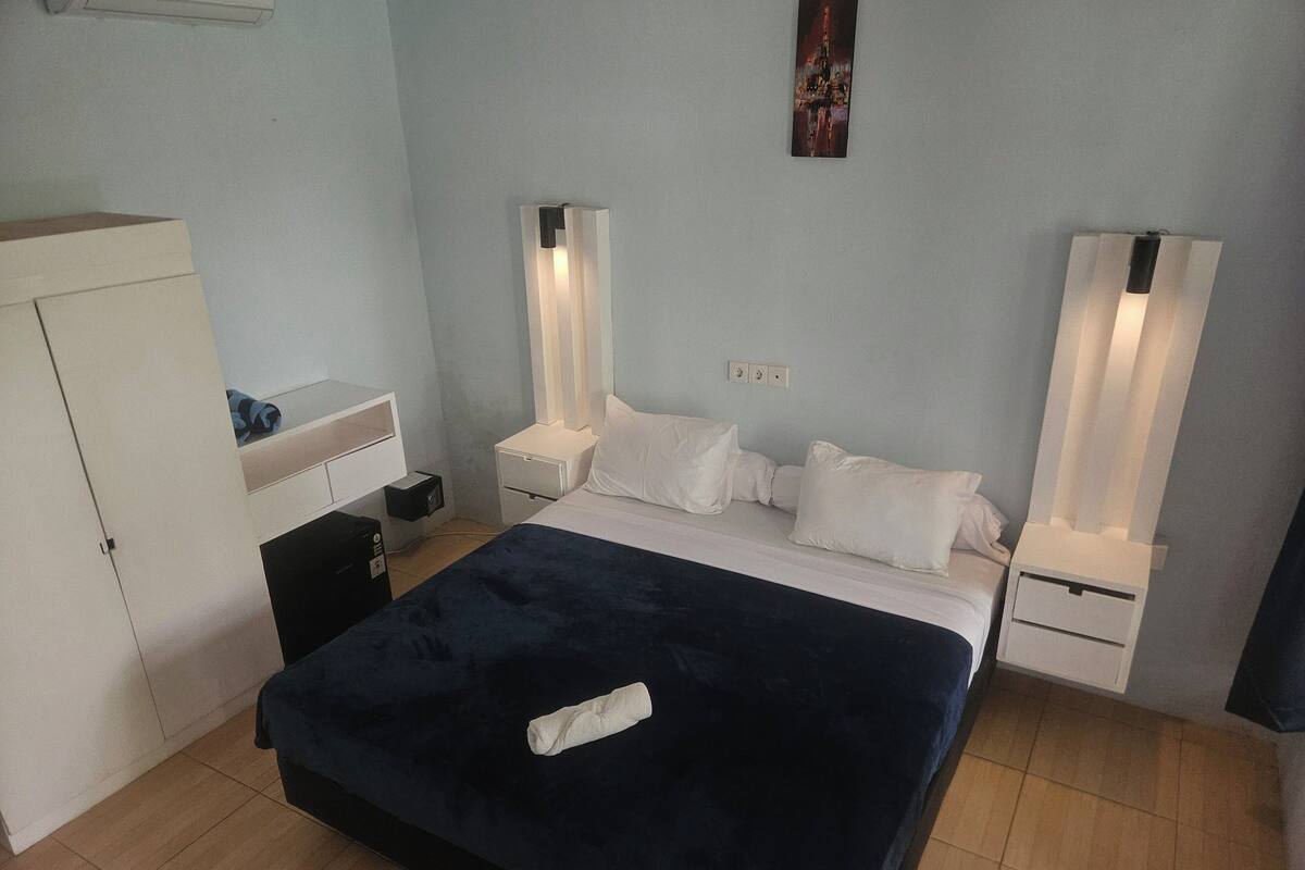 A bedroom with a large bed, two bedside tables, a wardrobe, and a nightstand.
