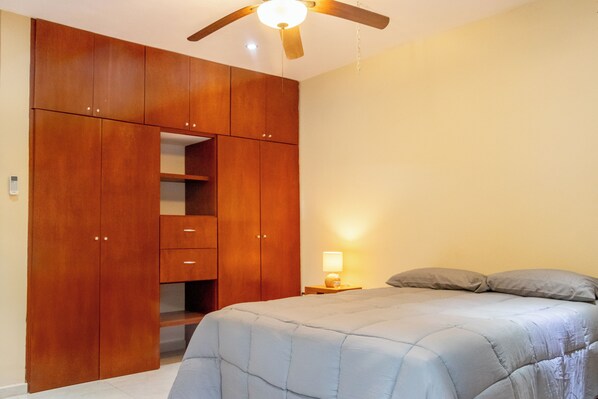 A bedroom with a bed, a wooden wardrobe, and a ceiling fan. - Apt with Pool & jungle in Puerto Morelos (Puerto Morelos)