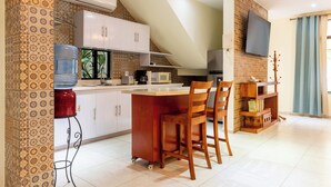 A kitchen with a bar area, white cabinets, a water dispenser, and a TV mounted on the wall. - Apt with Pool & jungle in Puerto Morelos (Puerto Morelos)