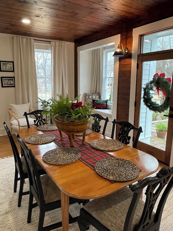 A dining room with a wooden table, black chairs, and a central plant.