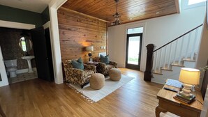 Un salón comedor amplio con techo de madera, una escalera y vista al exterior a través de un ventanal.