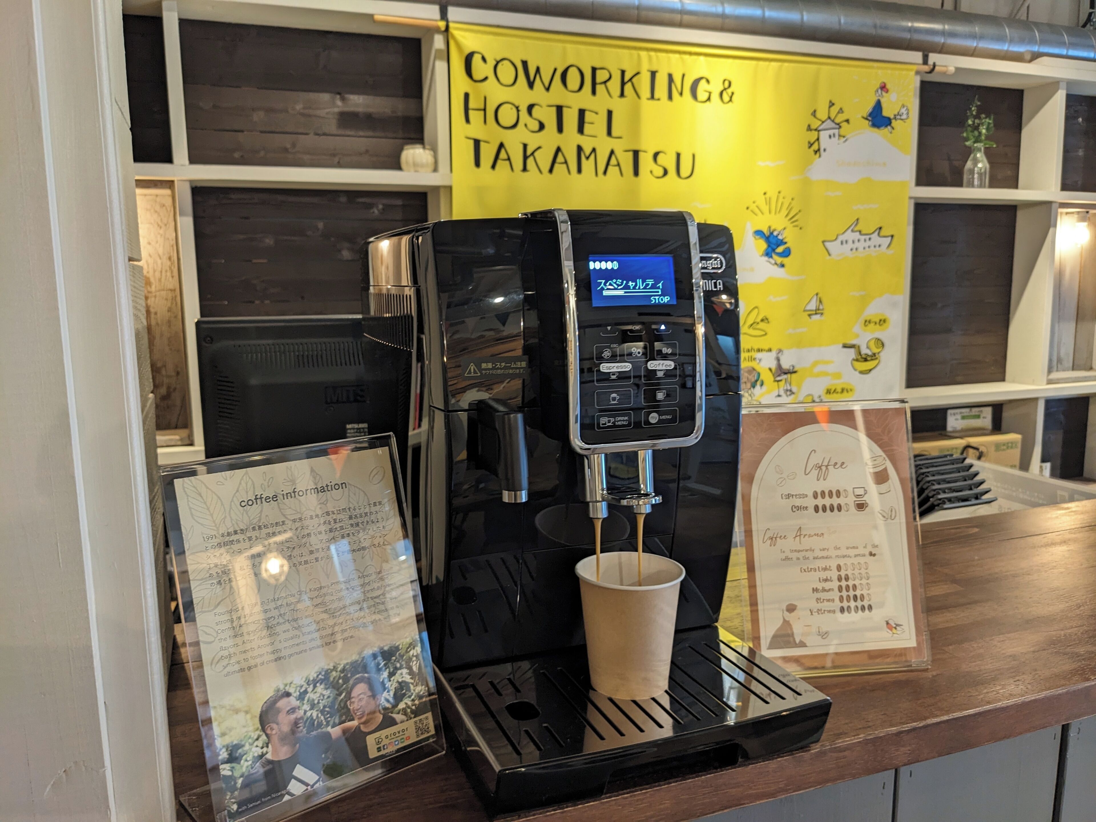 Una máquina de café con pantalla digital, una taza debajo del grifo y un cartel con información sobre el café.