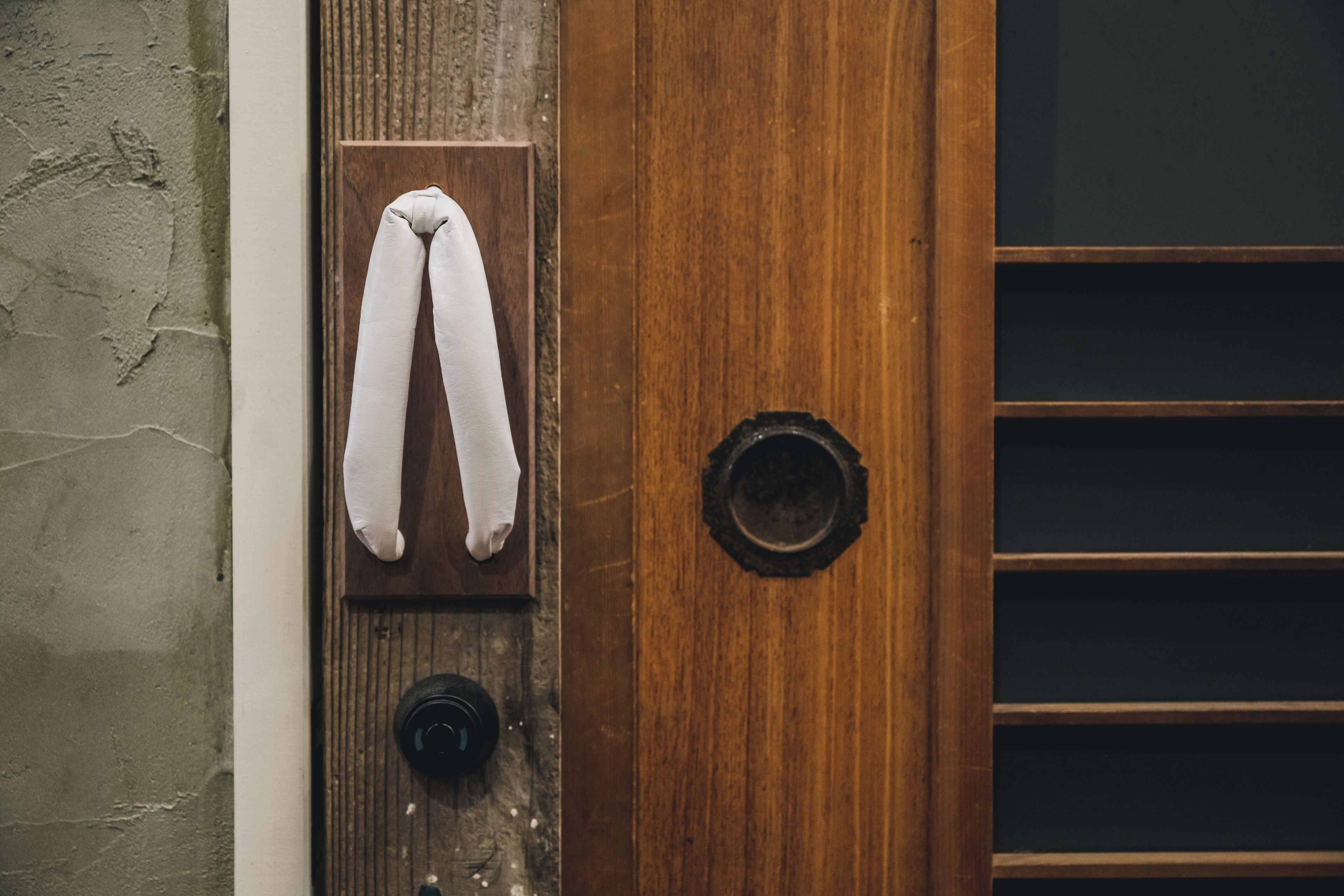 A wooden door with a towel hanging on a hook and a keyhole.