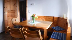 Une table à manger en bois, avec des chaises, un banc et un vase rempli de fleurs.