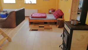 Una habitación pequeña y acogedora con una cama, un banco, una estufa y una ventana.