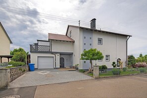 A two-story building with a garage, a small balcony, and a paved driveway.