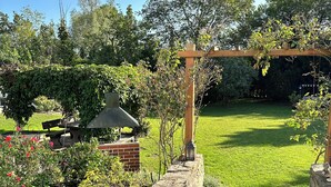 A garden patio with a stone pathway leading to a wooden pergola.