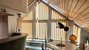 A modern kitchen with a curved countertop, a dining area with a round table and chairs, and a staircase with wooden slats.