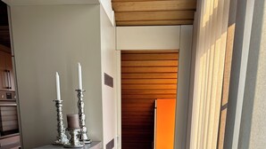 A narrow hallway with a wooden ceiling, a reception desk with a green countertop, and a woven mat at the entrance.