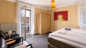 Une chambre d’hôtel avec un lit, un bureau, une chaise, une armoire et un tableau au mur.