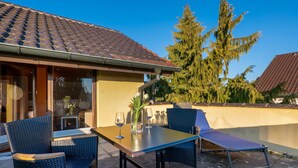 Eine Terrasse im Freien mit Tisch, Stühlen und einer Liege.