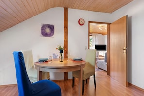 Un coin repas comprenant une table ronde, des chaises, une horloge et une porte donnant sur une autre pièce.