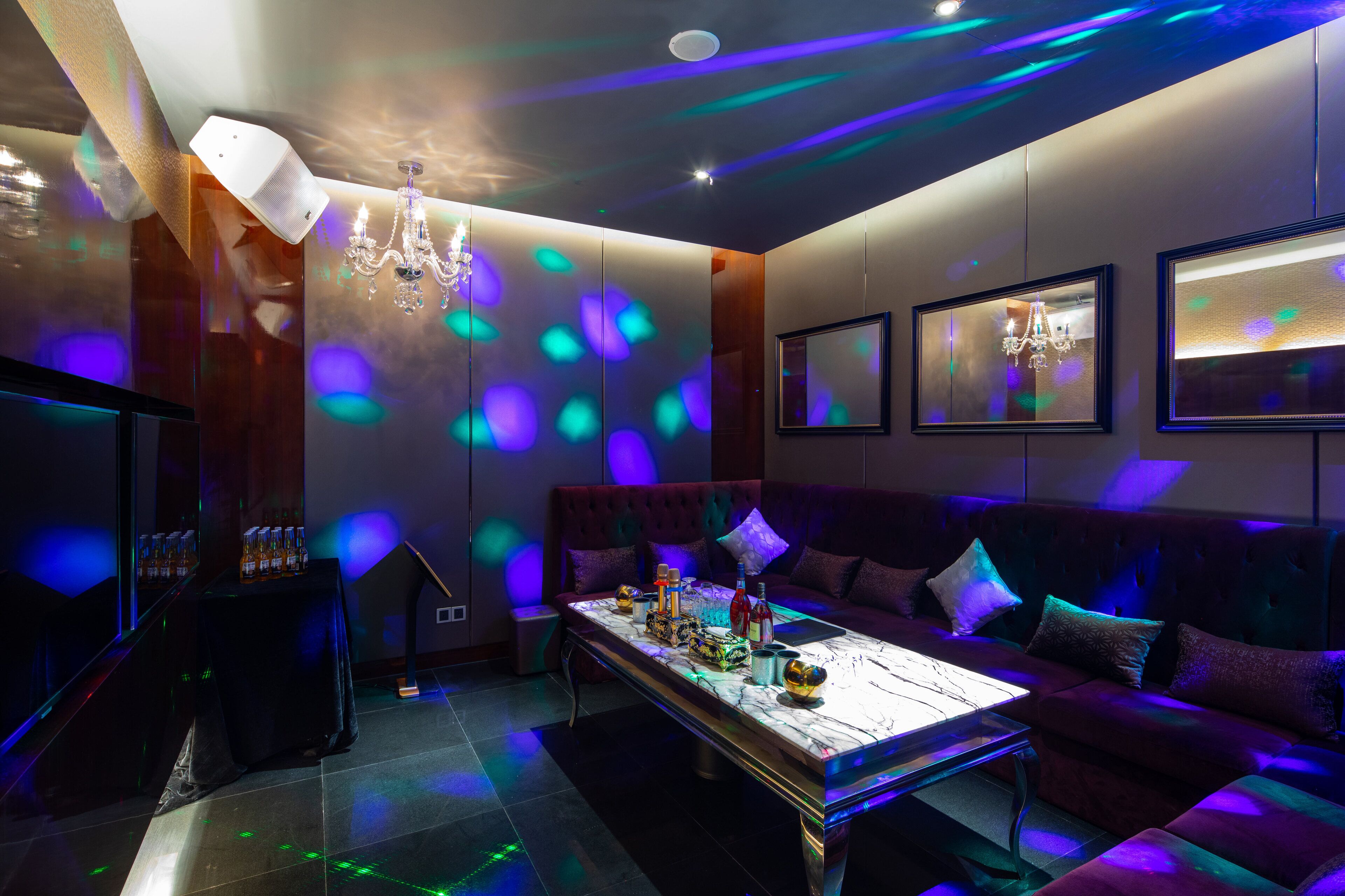 A modern lounge with a plush red sofa, a marble coffee table, and ambient lighting.