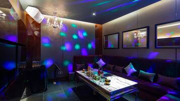 A modern lounge with a plush red sofa, a marble coffee table, and ambient lighting.