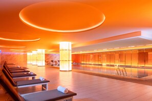 A modern spa with massage tables, a large illuminated pillar, and a reflective wall. - Rocase Hotel Wuxi (Wuxi)