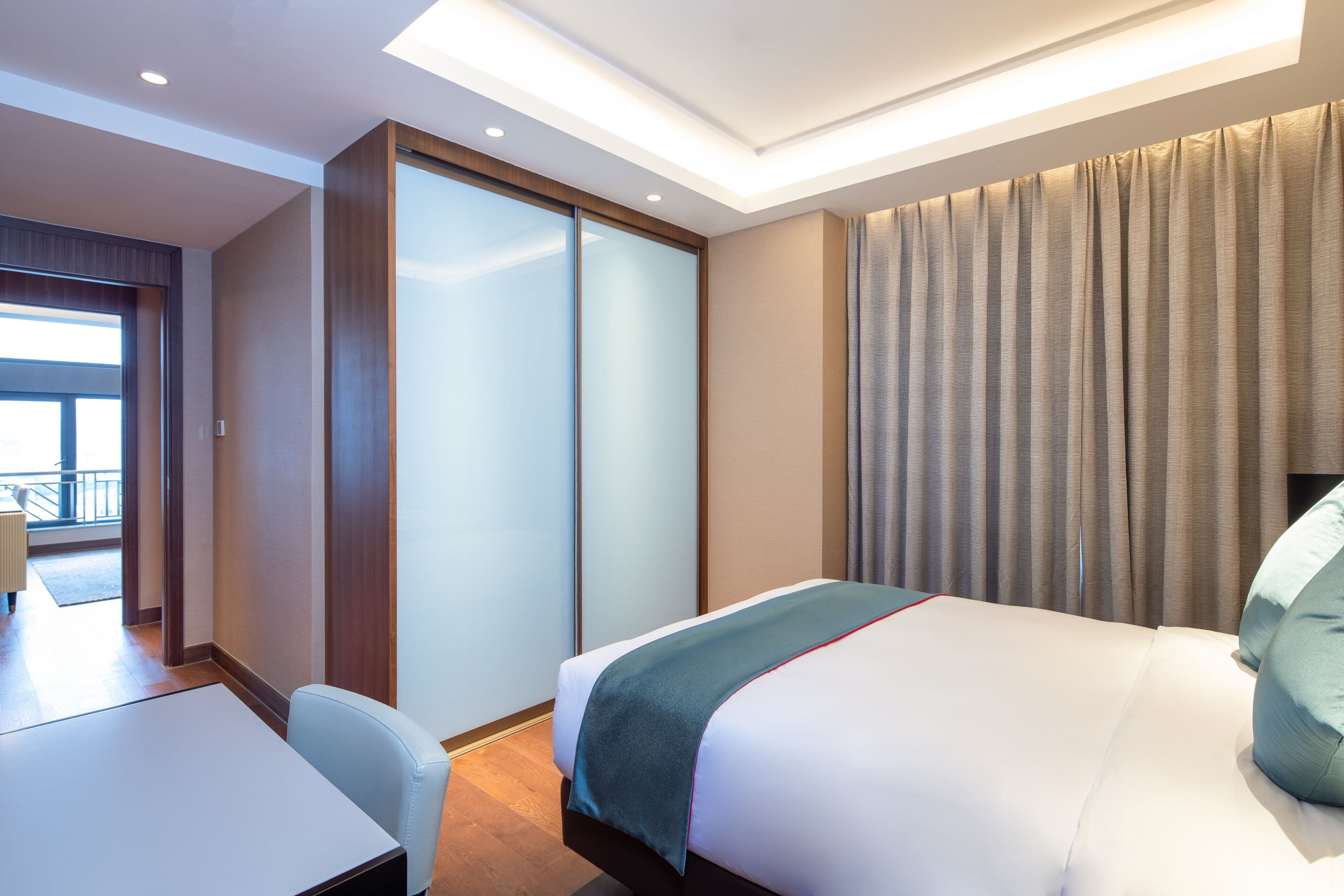 Een moderne hotelkamer met een bed, een bureau en een schuifdeur naar een balkon.