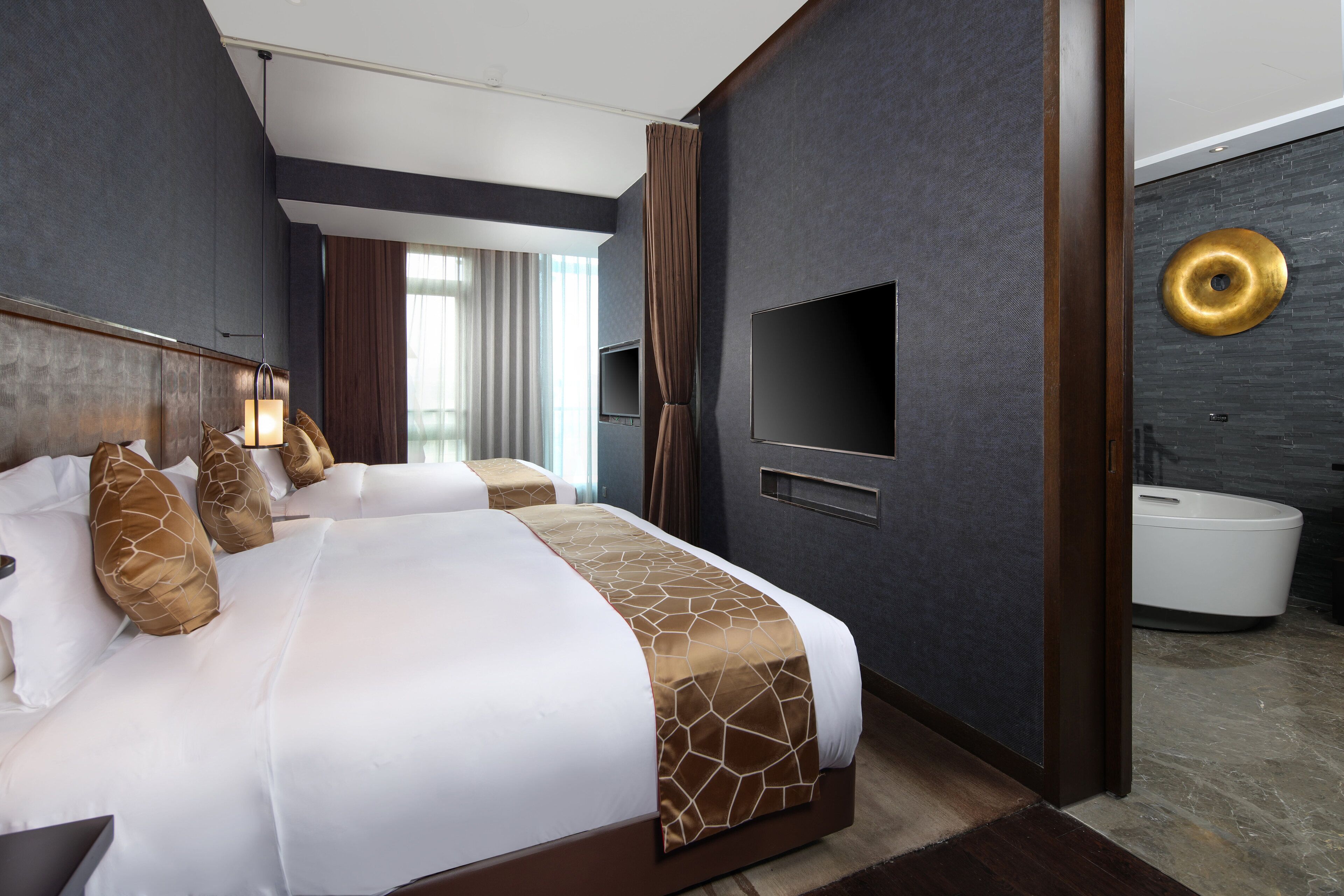 A modern hotel room with a large bed, a flat-screen TV, and a bathroom with a white sink and toilet.