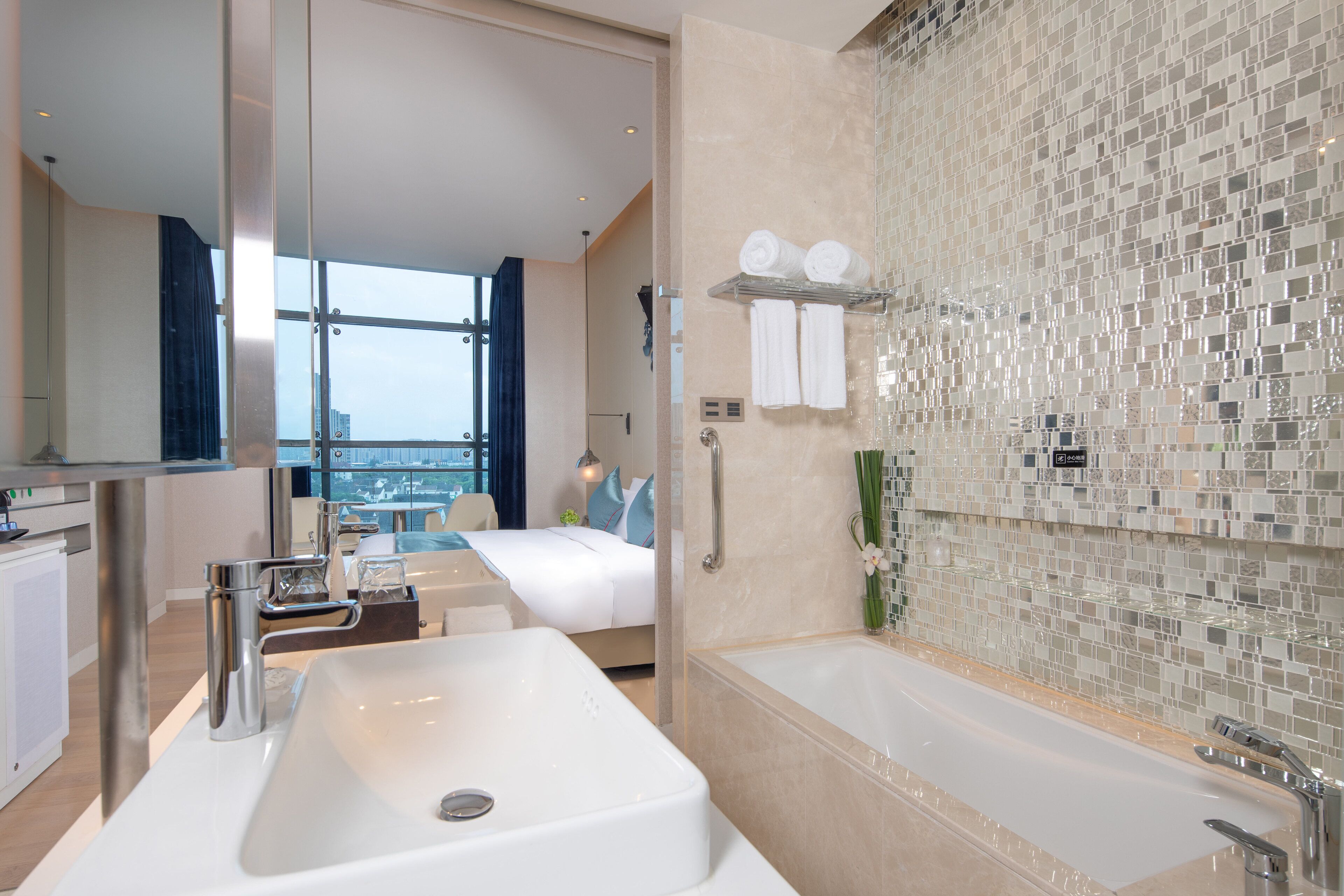 A modern hotel bathroom with a large sink, bathtub, and a shower area.