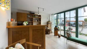 A room with a wooden reception desk, a chair, a window with a view of the outside, and shelves with various items.