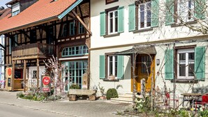 A traditional European building with a wooden balcony, a stone fountain, and a sign for a restaurant.