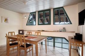Un comedor con una mesa y sillas de madera, una estantería con objetos y una ventana con vistas.
