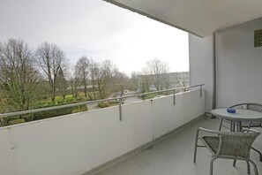 A balcony with a railing, a table, and two chairs.