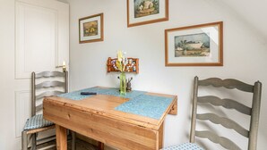 A dining area with a wooden table, chairs, and wall-mounted artwork. - Apartment 'Nis Puk' with Private Terrace, Shared Garden and Wi-Fi (Rodenäs)