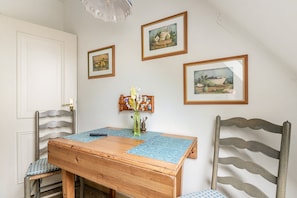 A dining area with a wooden table, chairs, and wall-mounted artwork.