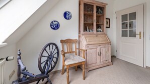 A room with a wooden cabinet, a chair, and a wall-mounted bicycle wheel. - Apartment 'Nis Puk' with Private Terrace, Shared Garden and Wi-Fi (Rodenäs)