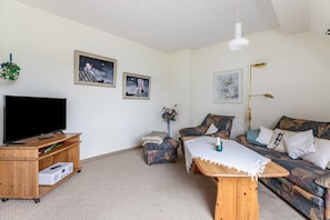 A living room with a flat-screen TV, wooden furniture, a sofa, and wall art.