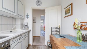A kitchen with white cabinets, a coffee maker, and a clock on the wall. - Apartment 'Nis Puk' with Private Terrace, Shared Garden and Wi-Fi (Rodenäs)
