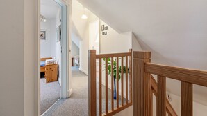 A hallway with a wooden railing, a plant, and a door leading to a bedroom with a bed and a desk. - Apartment 'Theodor Storm' with Private Terrace, Shared Garden and Wi-Fi (Rodenäs)