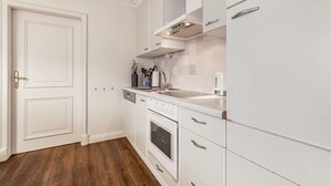 A kitchen with white cabinetry, a built-in oven, and a dishwasher. - Apartment 'Theodor Storm' with Private Terrace, Shared Garden and Wi-Fi (Rodenäs)