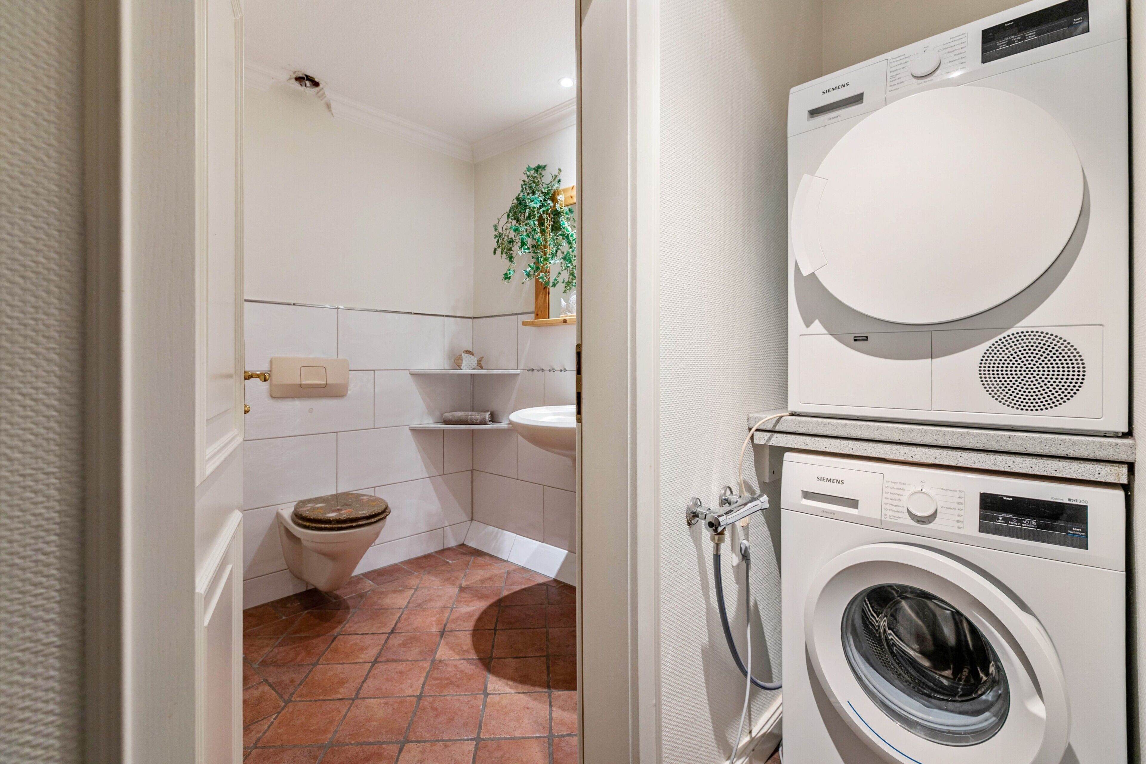 Ein Waschraum mit Waschmaschine und Trockner, Toilette und Waschbecken.