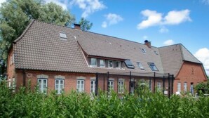 A large brick building with multiple windows and a sloped roof. - Apartment 'Theodor Storm' with Private Terrace, Shared Garden and Wi-Fi (Rodenäs)