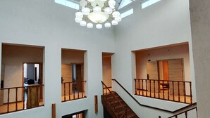 A multi-level interior with a central staircase, large windows, and a chandelier. - Hills Hotel karakol (Karakol)