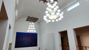 An interior with a large blue painting, a chandelier, and a wooden ceiling structure. - Hills Hotel karakol (Karakol)