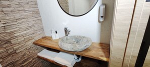 A bathroom with a stone sink, wooden vanity, and a stone wall. - Hills Hotel karakol (Karakol)