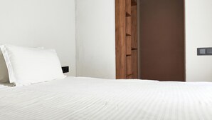 A neatly made bed with white linens, a wooden wardrobe, and a white wall. - Hills Hotel karakol (Karakol)